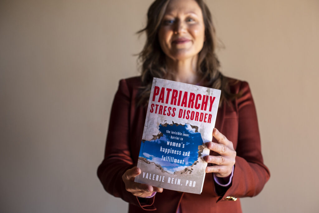 Dr. Valerie Rein, author of Patriarchy Stress Disorder, holds her book.